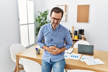 Poster - Middle age hispanic man with beard wearing business clothes at the office with hand on stomach because nausea, painful disease feeling unwell. ache concept.