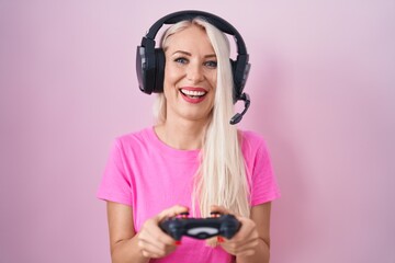 Poster - Caucasian woman playing video game holding controller smiling and laughing hard out loud because funny crazy joke.