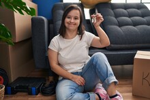 Down Syndrome Woman Smiling Confident Holding Key Sitting On Floor At New Home