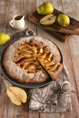 Wall Mural - Autumn baking: homemade pear pie and ripe pears on a light wooden table. Open pie with pears and caramel. Photo in rustic style.