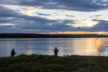 Silhouette Of Two Fishermen On The Bank Of The Egegik River In Alaska During The Early Morning Sunrise. 