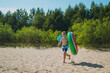 © Yulia Raneva - cute caucasian boy carrying rubber ring and butterfly net running into water with laughter.