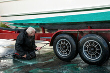 Man Pressure Washing Power Boat On A Transport Trailer