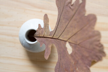 Sticker - abstract autumn oak leaf inside a white vase (viewed from above) on wood