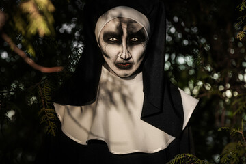 Portrait of scary devilish nun near tree outdoors. Halloween party look