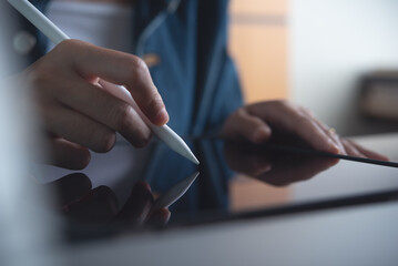 Poster - Woman working on digital tablet pc, using stylus pen touching on touchpad screen on office table, close up