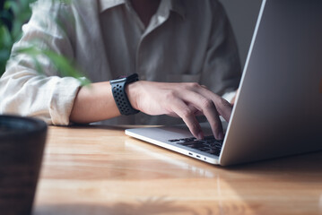 Wall Mural - Business man working on laptop computer, typing on laptop keyboard on office table, surfing the internet, online job, online study, e-learning, working at home, telecommuting concept