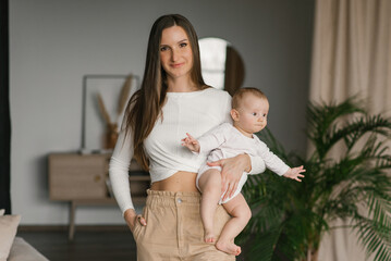 happy young loving mother holds a small child, a son, a baby at home in her arms. the concept of mot