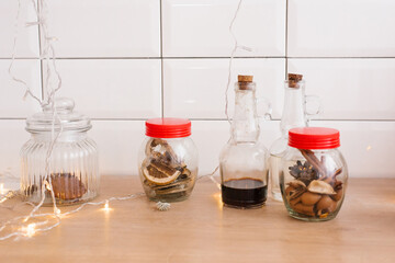 Wall Mural - Glass jars of dried fruit, bottled sauce and Christmas lights in a Scandinavian kitchen