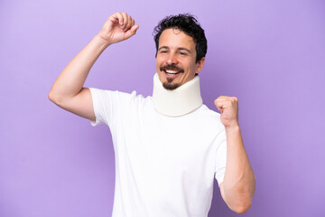 Young caucasian man wearing neck brace isolated on purple background celebrating a victory