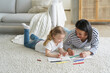 © VK Studio - Kid girl daughter and mom drawing painting lying on floor carpet together. Children's education