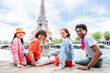 Multiethnic group of young happy teens friends bonding and having fun while visiting Eiffel Tower area in Paris, France