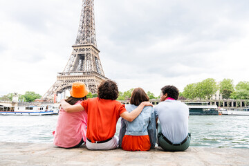 Multiethnic group of young happy teens friends bonding and having fun while visiting Eiffel Tower area in Paris, France