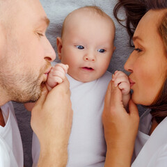 Wall Mural - Happy parents with his newborn baby, top view. Happy family. Healthy newborn baby with mom and dad. Close up Faces of the mother, father and infant baby. Cute Infant boy and parents.