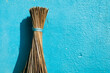 Coconut broom stick isolated in blue color painted wall background. Traditional cleaning broom stick used in India from olden days.
