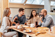 © Andrii - A cheerful group of friends is eating delicious pizza in a restaurant. Friends are sitting in a restaurant and having fun.