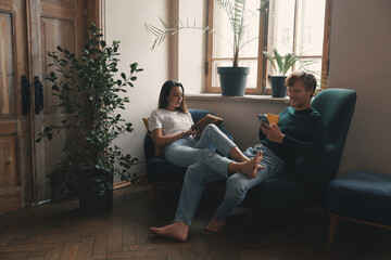 Wall Mural - Cheerful young couple enjoying free time while relaxing at home together