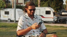 Happy Man Using Phone, Smartphone Owner Motor Home, Using Phone And Relax, Making Selfie With Application, Camping Van Driver Smiling, Tourist Rent Bus Trailer For Camping.
