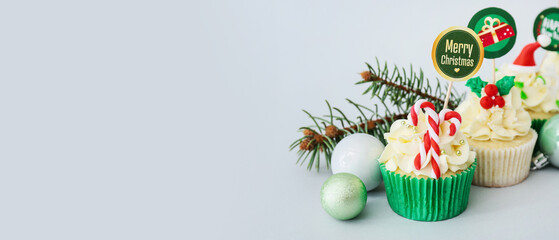 Tasty Christmas cupcakes on light background with space for text