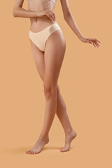 Wall Mural - Slim young woman in underwear on beige background