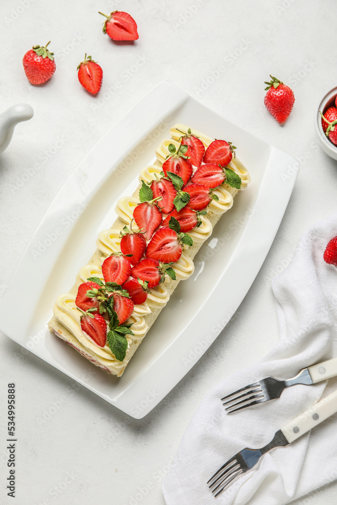 Plate of delicious roll cake with fresh strawberry on light background