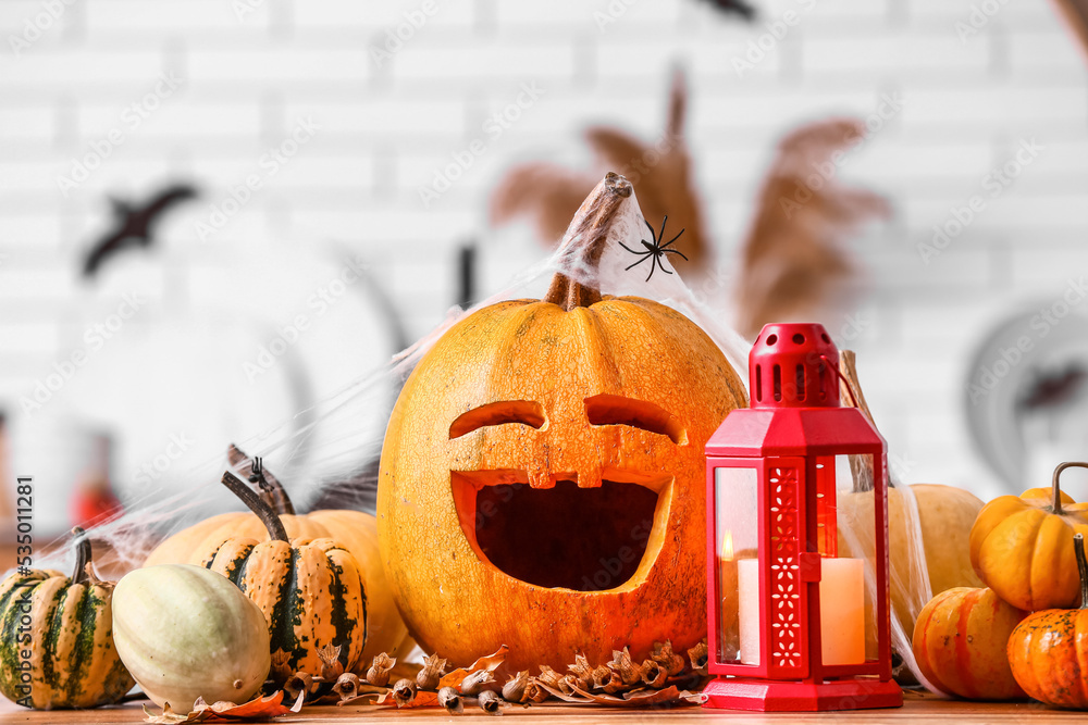 Halloween pumpkins with lantern and fallen leaves on counter in kitchen