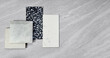 top view of interior material samples contains gloss and matt grey tiles, black and white terrazzo artificial stone, white marble quartz placed on grey travertine background. interior material board.