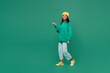 Full body fun side view little kid teen girl of African American ethnicity 13-14 year old wear casual hoody hat walking go point finger aside isolated on plain dark green background Childhood concept