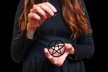 Woman in black dress with pentagram necklace on black