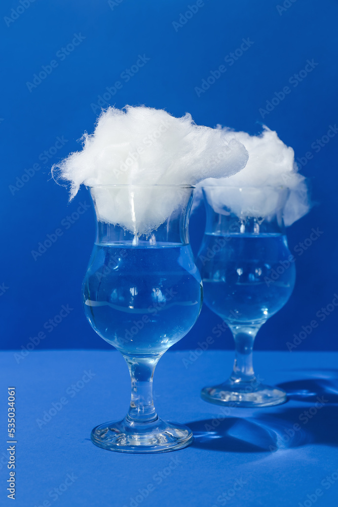 Glasses with tasty cotton candy cocktail on blue background