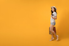 Beautiful Asian shopaholic woman smiles and happy while carrying shopping bags and credit card on yellow background. Summer sale, Mid-year sales concept.