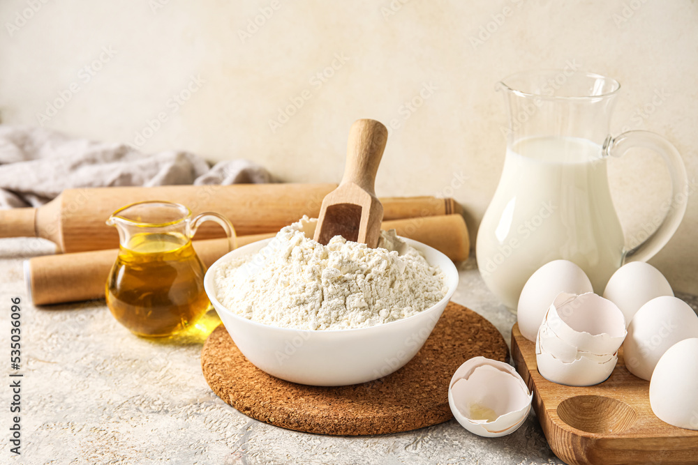 Bowl with flour and ingredients for baking on light table