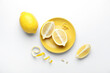 Plate with fresh lemons and peel on white background