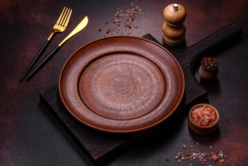 An empty brown ceramic plate on a dark concrete brown background