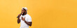 young handsome african american boy singing emotional with microphone isolated on yellow background, in motion gesturing