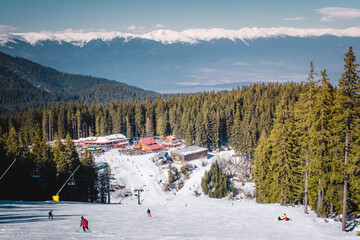 Wall Mural - Winter landscape with panorama of Bansko above the clouds. Famous ski resort in Bulgaria. View of the ski slopes and the Pirin Mountains