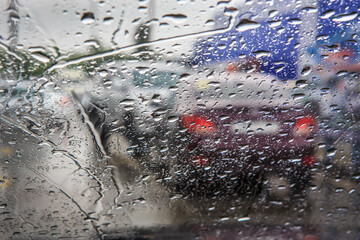 Wall Mural - view through the wet windshield of car on city road during rainstorm