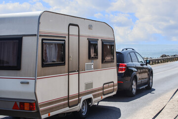 Poster - Car with a camper trailer moves along the road