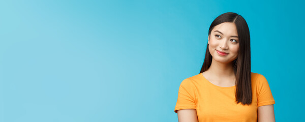 Wall Mural - Close-up dreamy hopeful charming young asian woman wear yellow t-shirt turn sideways smiling delighted, contemplate beautiful summer scenery outside window sit office carefree, blue background