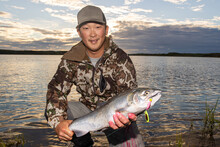 Happy Fisherman Holding Fresh Caught Silver Coho Salmon On The Bank Of Egegik River In Alaska