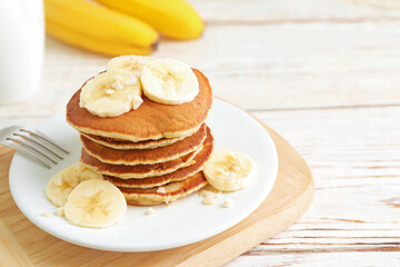 Wall Mural - Plate of banana pancakes served on white wooden table, closeup. Space for text