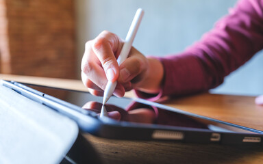 Wall Mural - closeup of a hand using stylus pen technology for working and writing on digital tablet screen