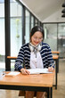 © bongkarn - Portrait, Smart Asian female college student doing her homework, writing an essay