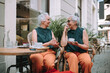 Happy senior women twins having coffee break in city, smiling and talking.