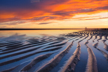 Wall Mural - A seascape during sunset. Lines of sand on the seashore. Bright sky during sunset. A sandy beach at low tide. Travel image. Photography for design.