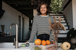 © Clique Images - Portrait of young African American woman wearing striped shirt standing at kitchen counter looking away smiling