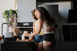 © Clique Images - Horizontal medium long shot of young women in love spending morning at home standing at kitchen counter flirting while making breakfast