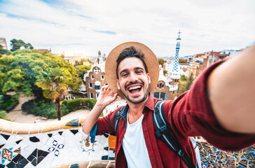 Wall Mural - Happy tourist take selfie self-portrait with smartphone in Park Guell, Barcelona, Spain - Smiling man on vacation looking at camera - Holidays and travel concept