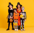 © JenkoAtaman - Happy Halloween! Kids in carnival costumes and makeup with pumkin basket smiling on bright colored yellow background