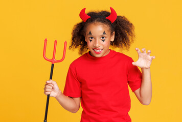 Happy cheerful ethnic girl in devil costume scary   gestures and celebrates Halloween  on a bright purple background